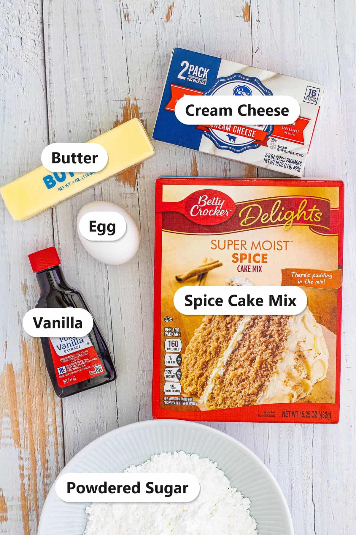 Labeled ingredients to make gooey butter cookies including cream cheese, butter, egg, vanilla, spice cake mix, and powdered sugar.