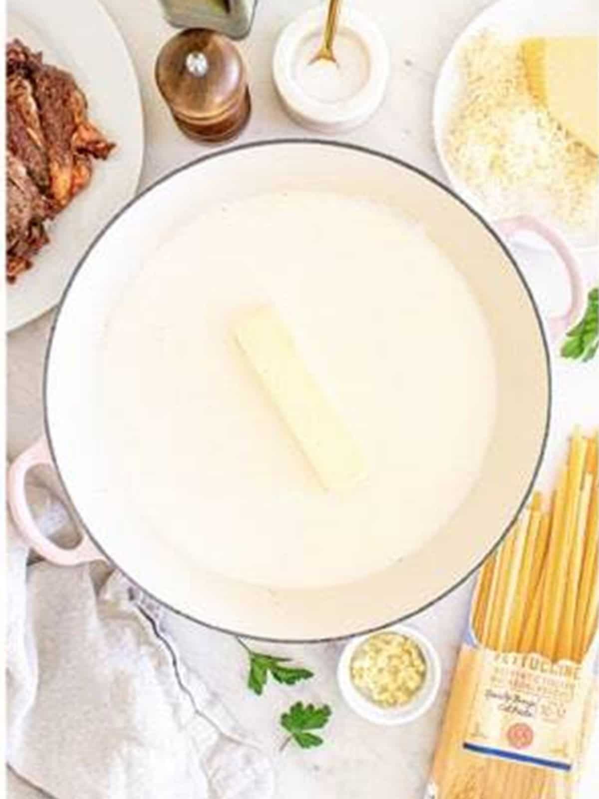 Butter and heavy cream simmering in a skillet for Steak Alfredo sauce.