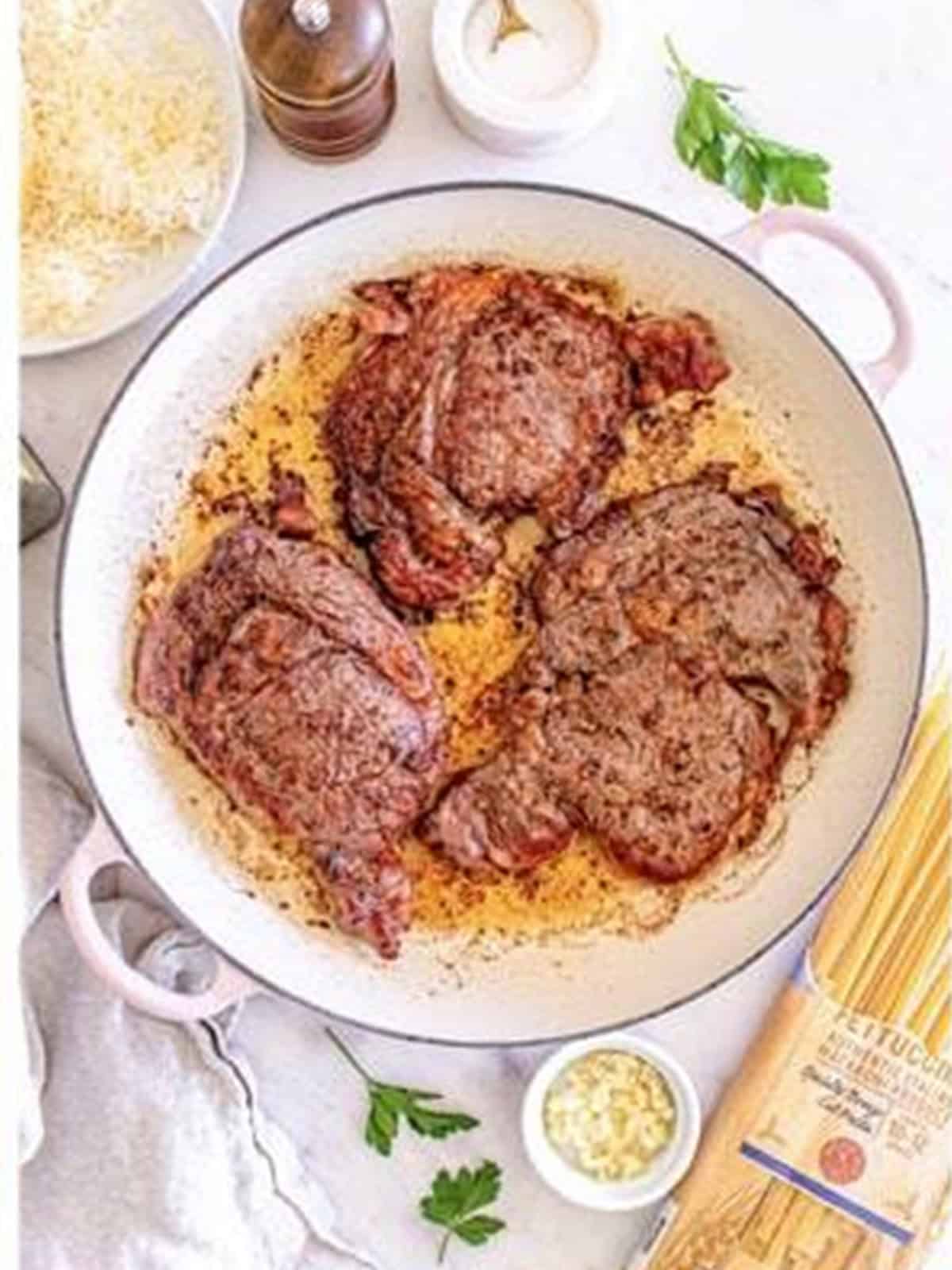 Ribeye steaks searing in a skillet until browned for Steak Alfredo.