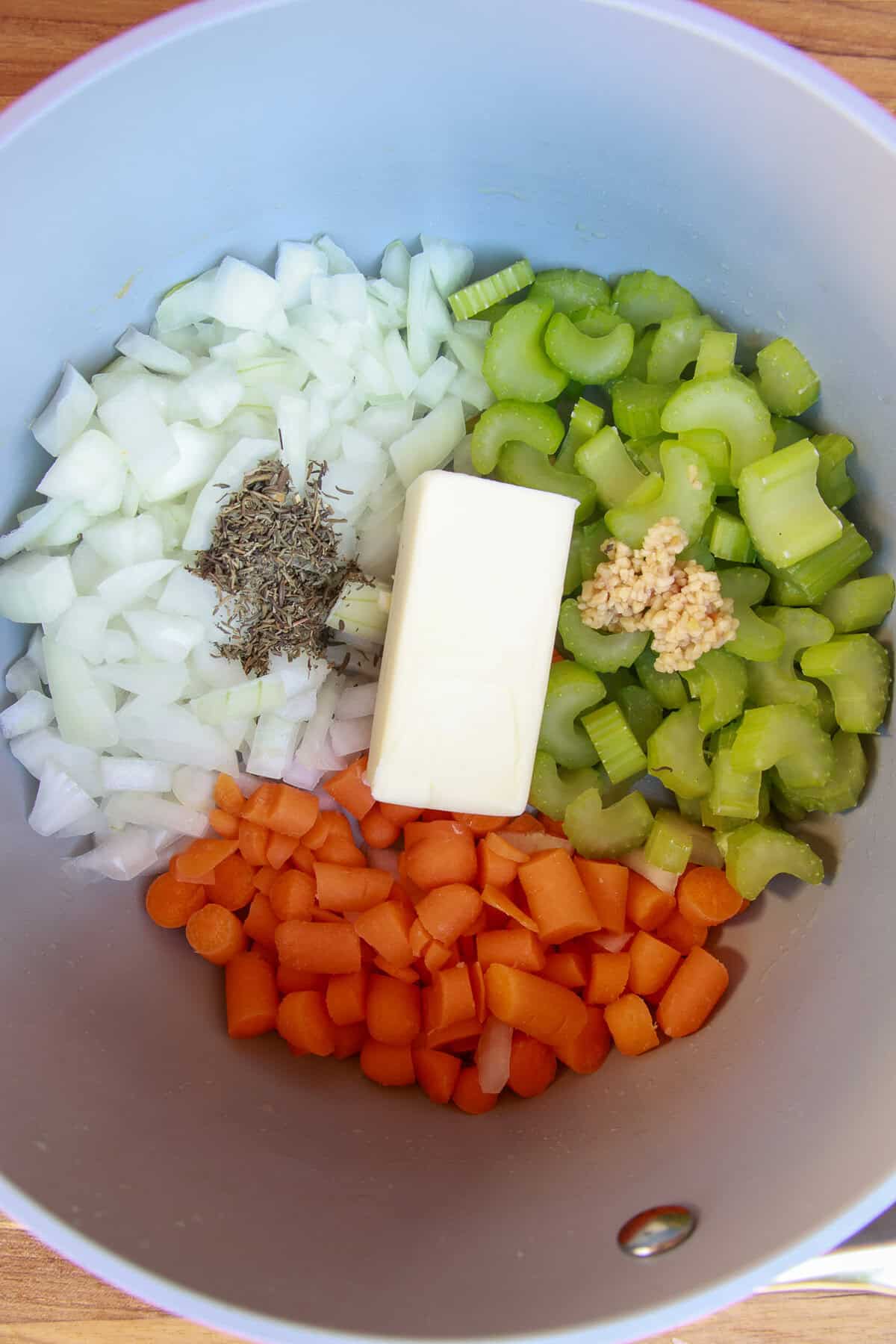 Diced onion, carrot, celery, garlic, thyme, and a stick of butter added to a pot.