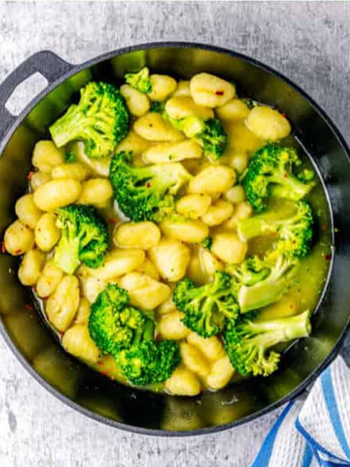 Chicken stock added to the gnocchi and broccoli simmering in the skillet