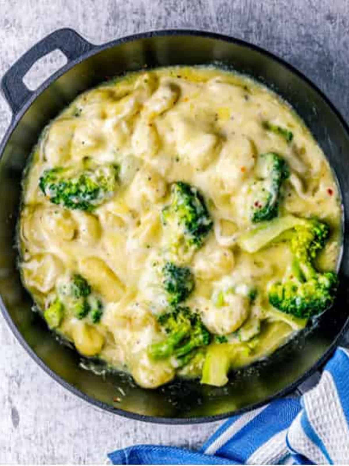 Creamy cream cheese sauce coating the gnocchi and broccoli in the skillet