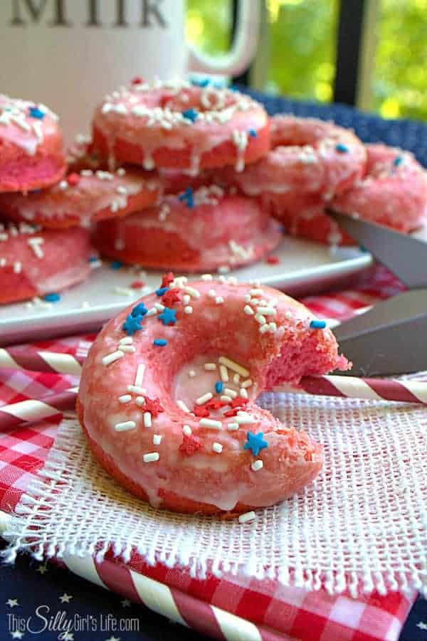 Strawberry donut with a bite taken out showing the soft pink cake inside
