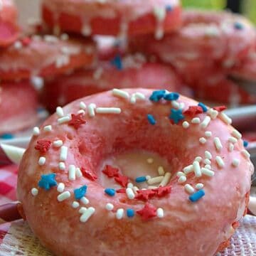 Close up of a glazed strawberry donut covered in white sprinkles