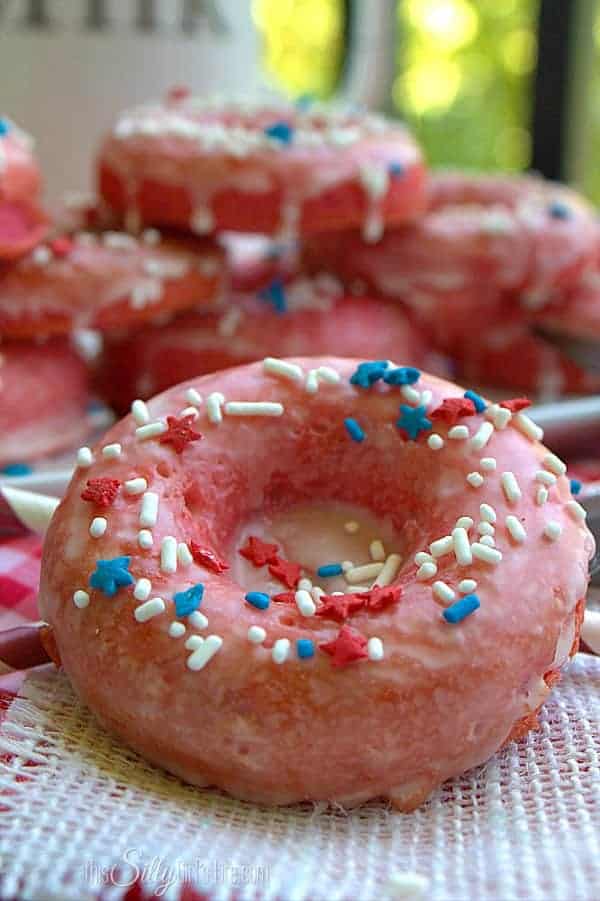 Close up of a glazed strawberry donut covered in white sprinkles