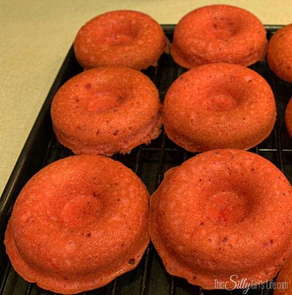 Baked strawberry donuts cooling on a wire rack