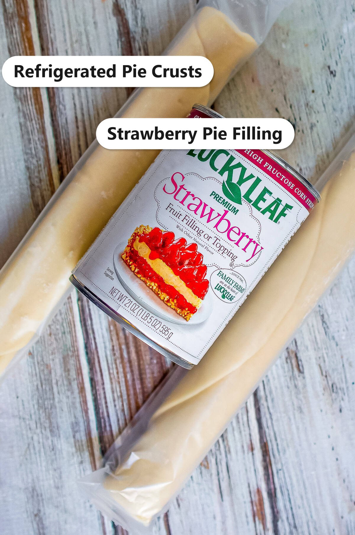 Labeled ingredients for strawberry hand pies showing refrigerated pie crusts and a can of strawberry pie filling.