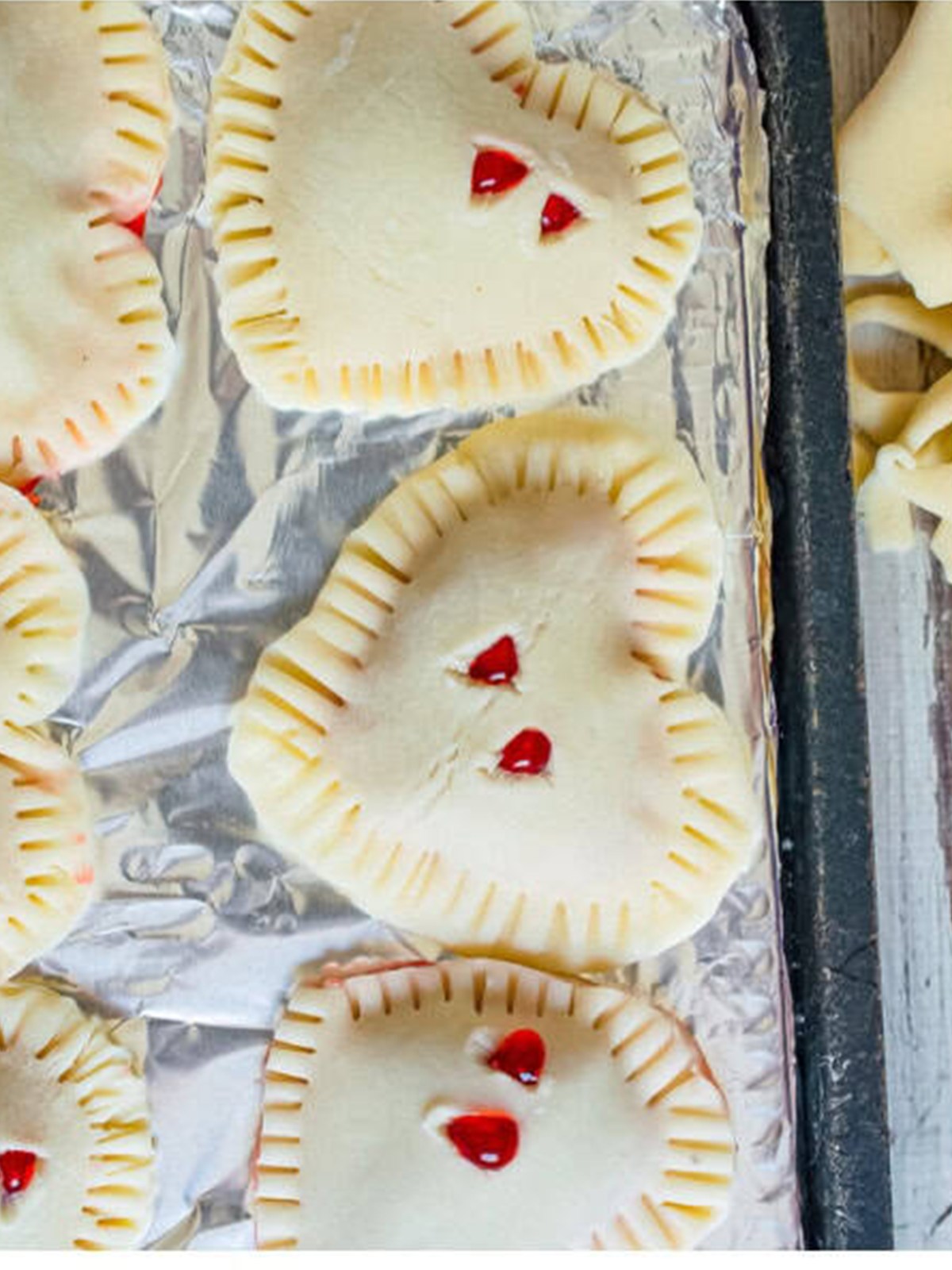 Hand pies crimped with a fork and vented on a foil lined baking sheet.
