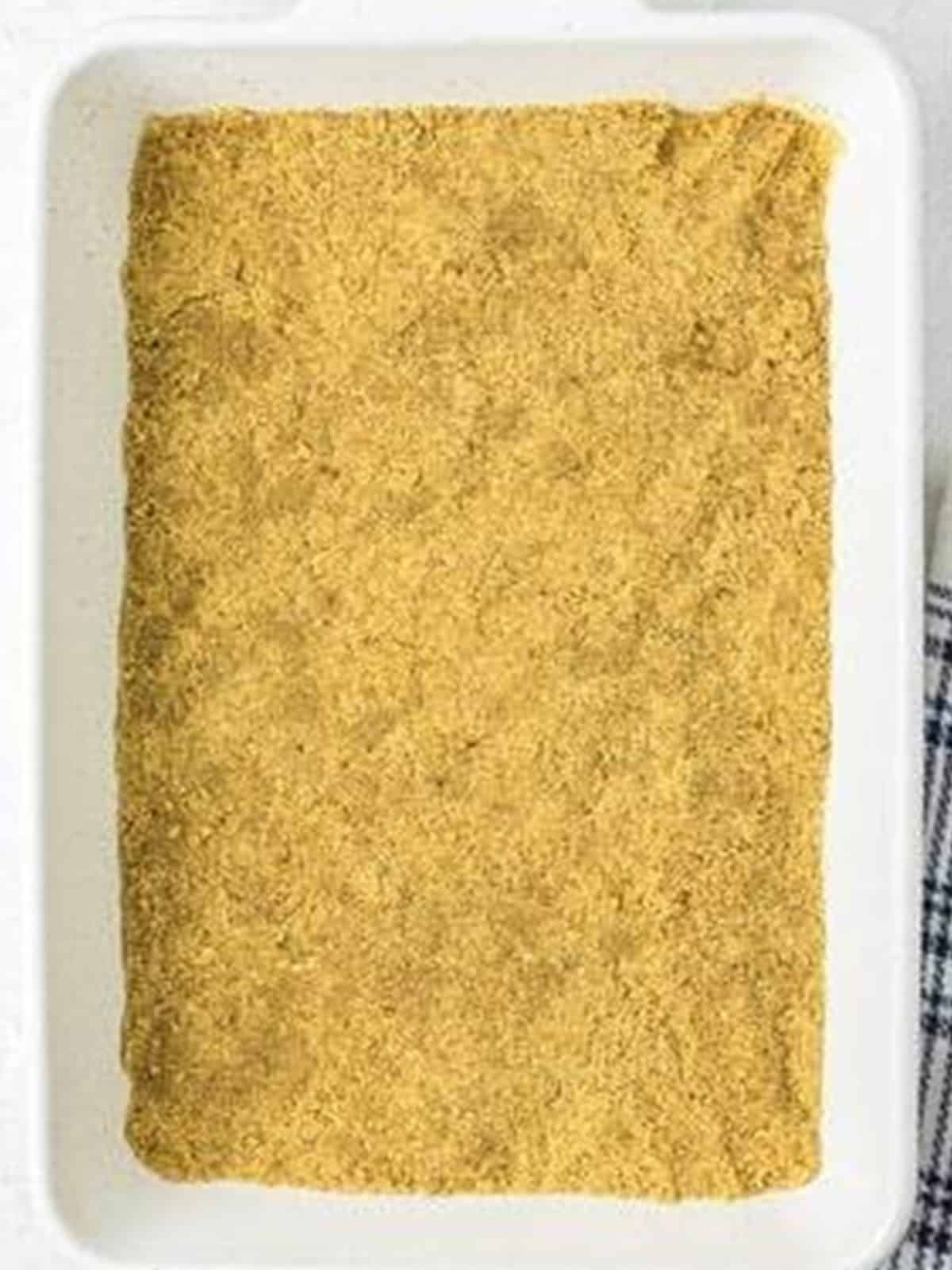Graham cracker crust pressed into the bottom of a white 9x13 baking dish for strawberry icebox cake.