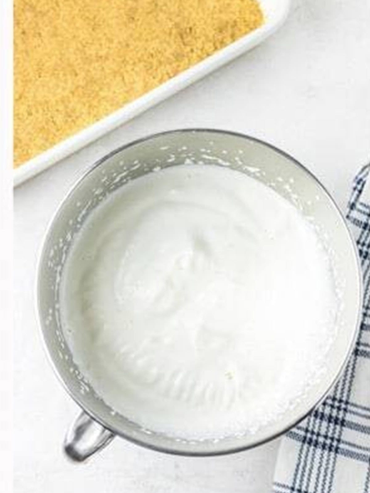 Evaporated milk whipped to stiff peaks in a metal bowl.