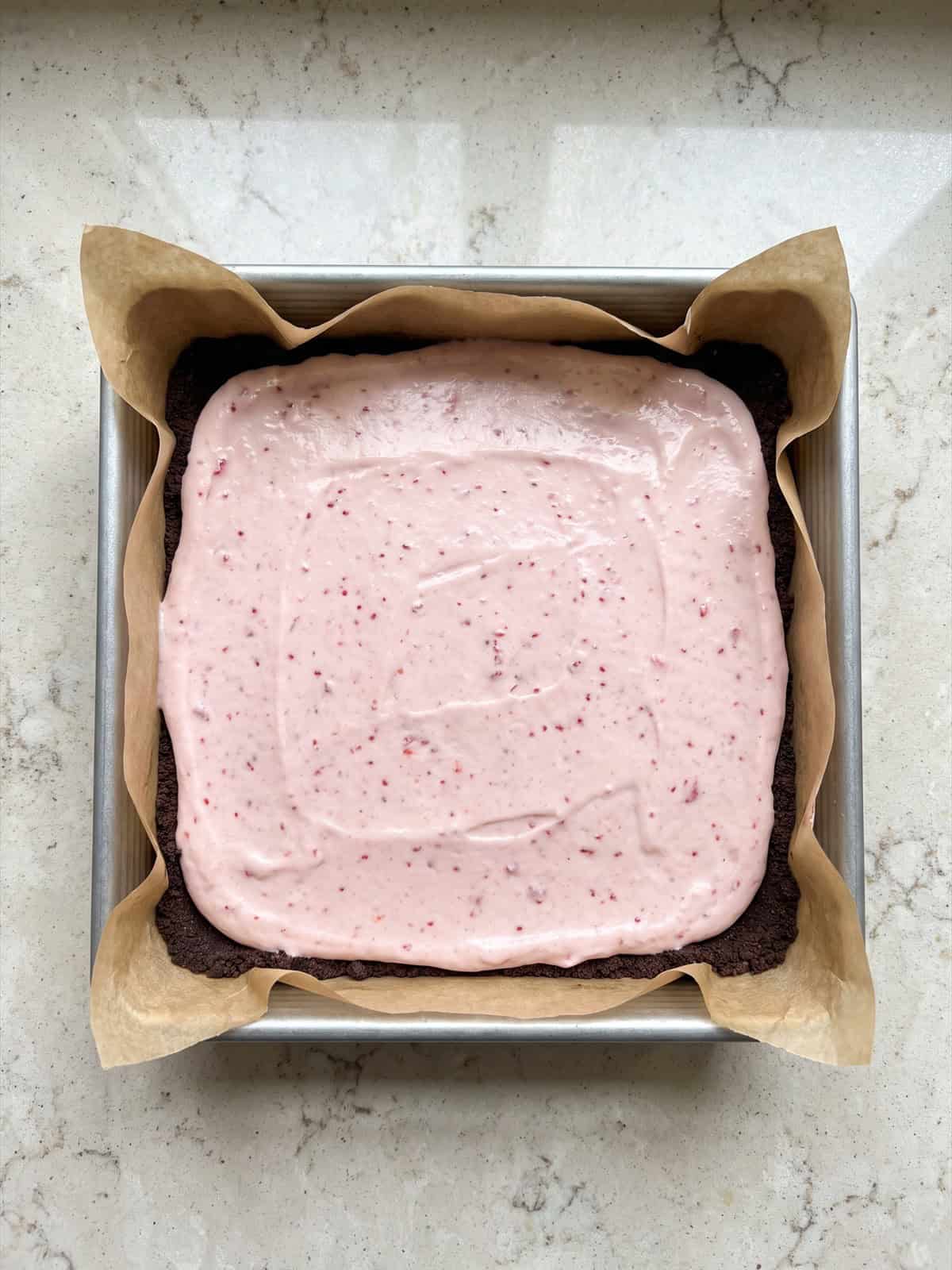 Strawberry cream filling smoothed over a chocolate cookie crust before freezing.