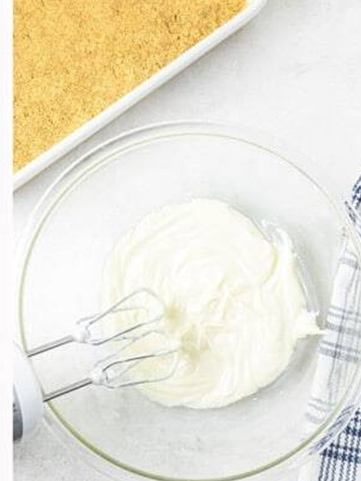Cream cheese whipped smooth in a glass bowl with a hand mixer.