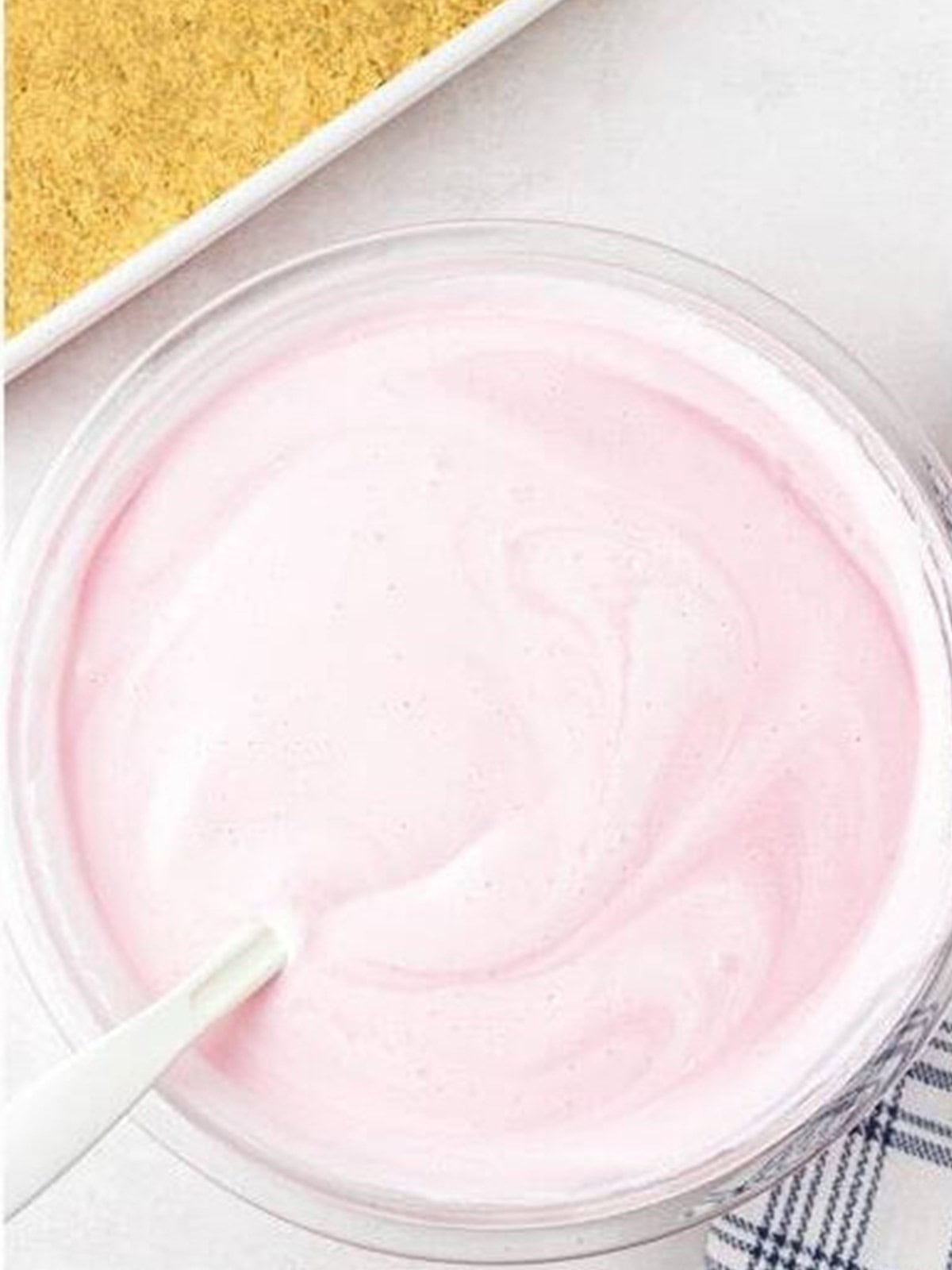 Smooth pink strawberry icebox cake filling folded together in a glass bowl.