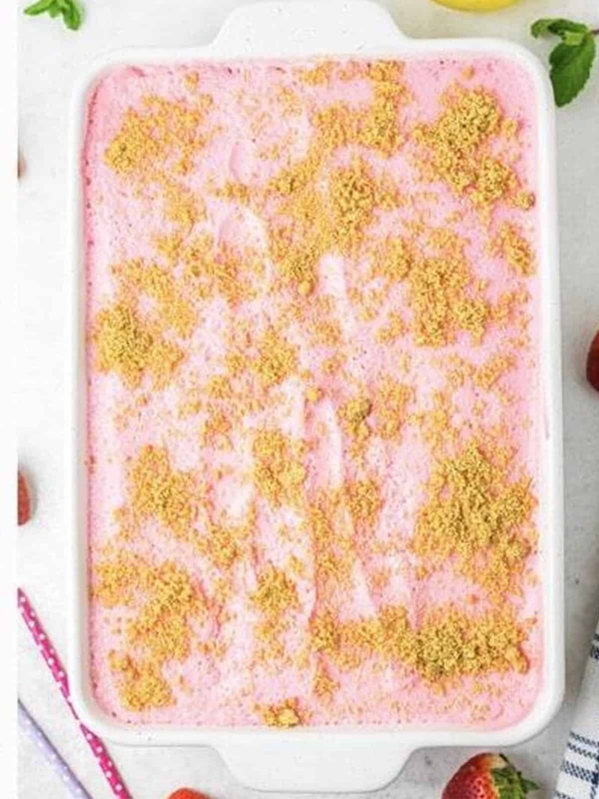 Finished no bake strawberry icebox cake topped with graham cracker crumbs in a white baking dish.