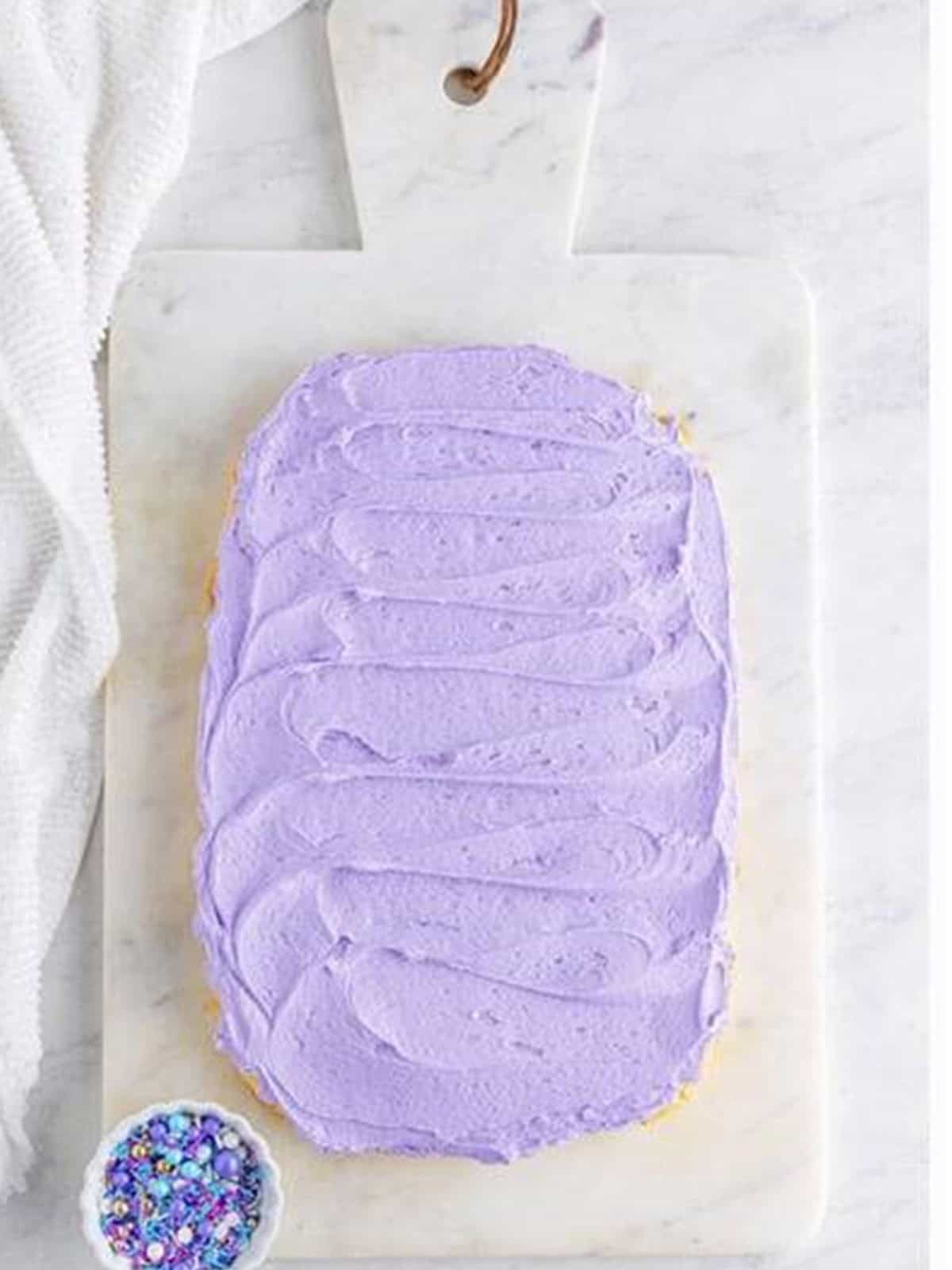 Purple buttercream frosting spread over the sugar cookie bar base.