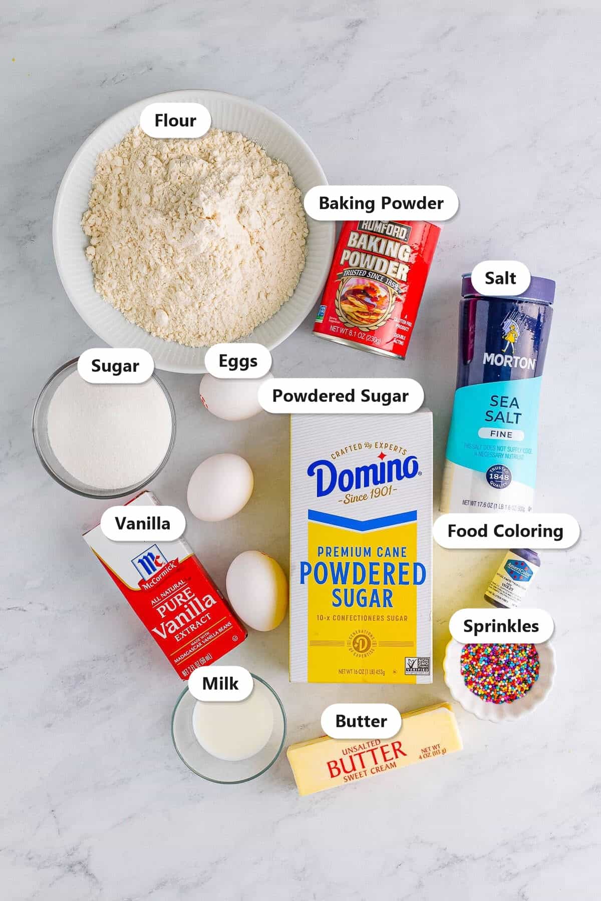 Labeled ingredients for frosted sugar cookie bars including flour, sugar, butter, eggs, powdered sugar, sprinkles, and food coloring.