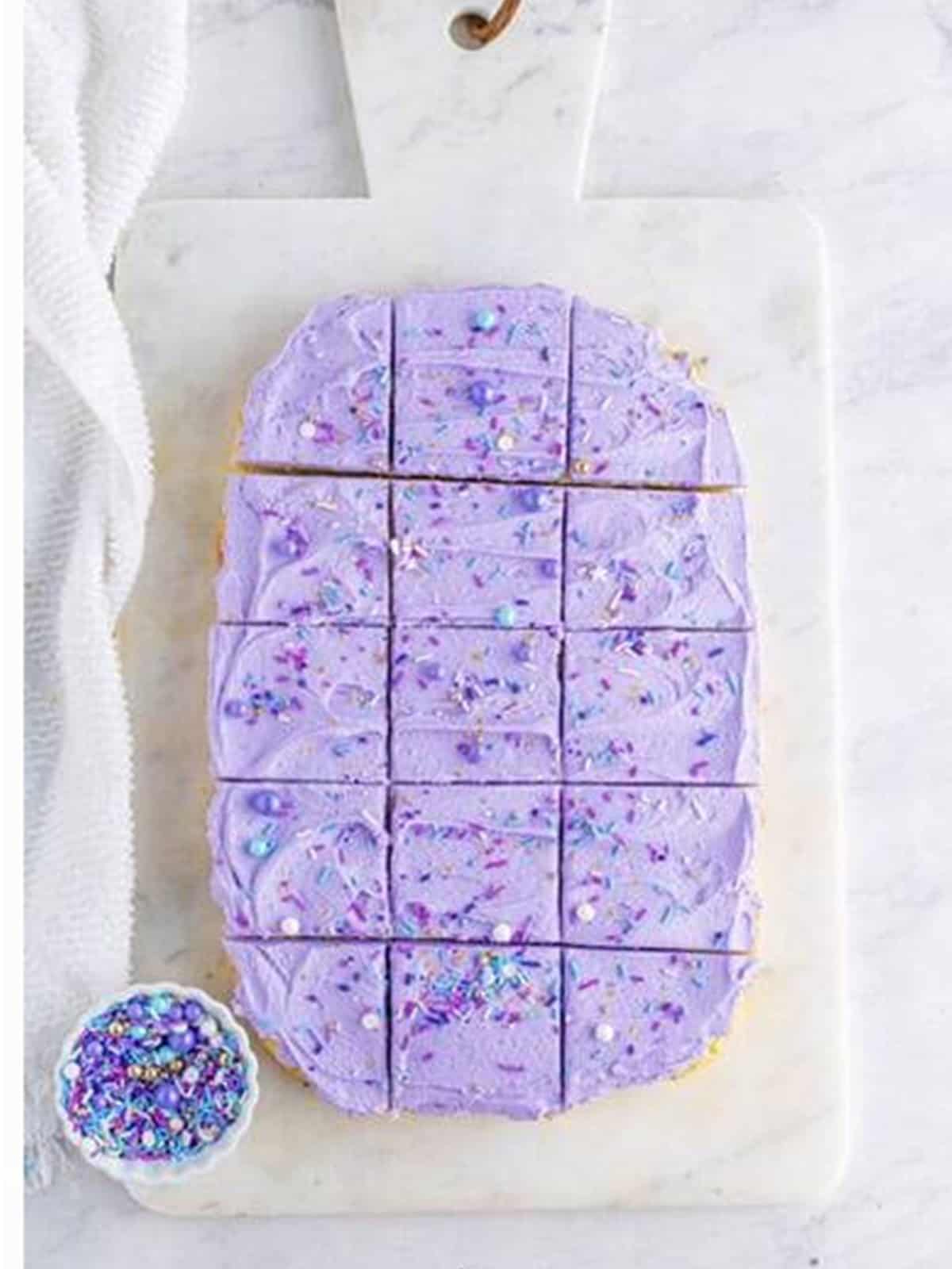 Frosted sugar cookie bars topped with sprinkles and cut into squares.