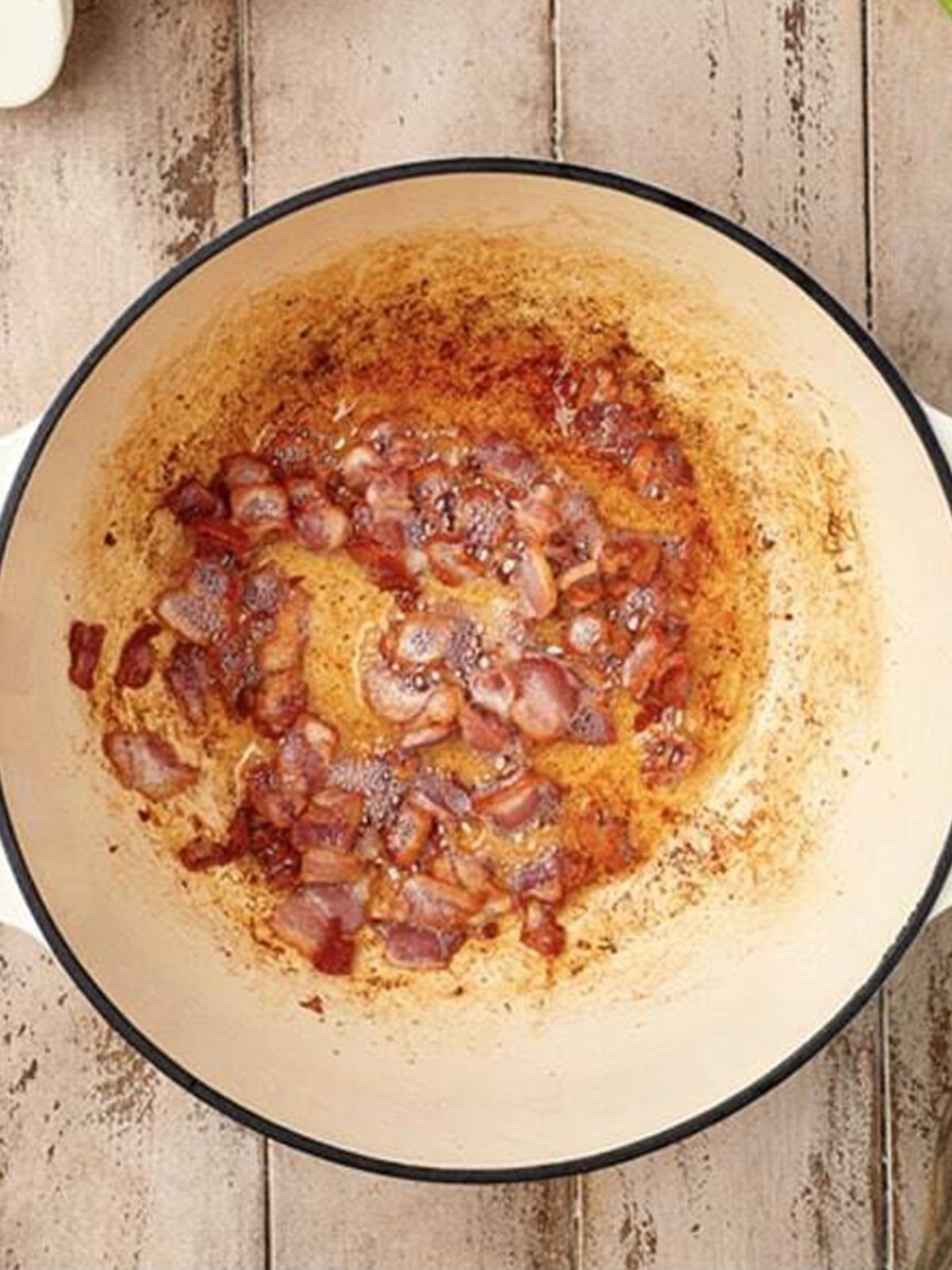 Crispy bacon cooked and rendered in a large pot for sweet and sour cabbage.