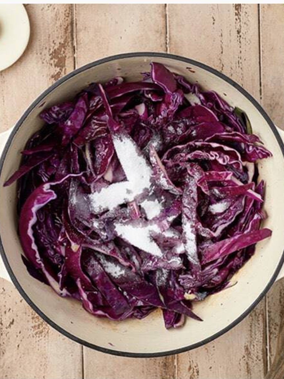 Red cabbage seasoned with salt, pepper, vinegar, sugar, and water in a pot.