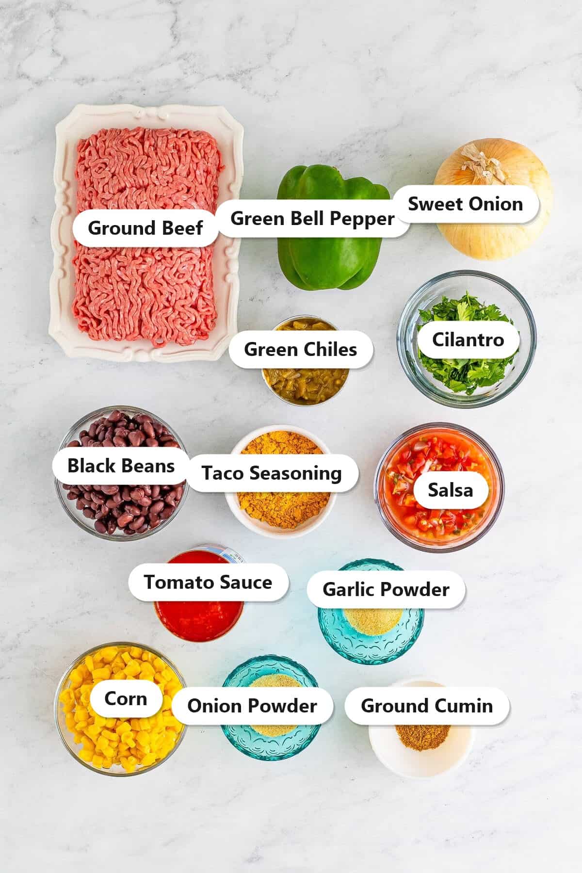 Labeled ingredients to make Taco Joes including ground beef, black beans, corn, green chiles, salsa, and taco seasoning.