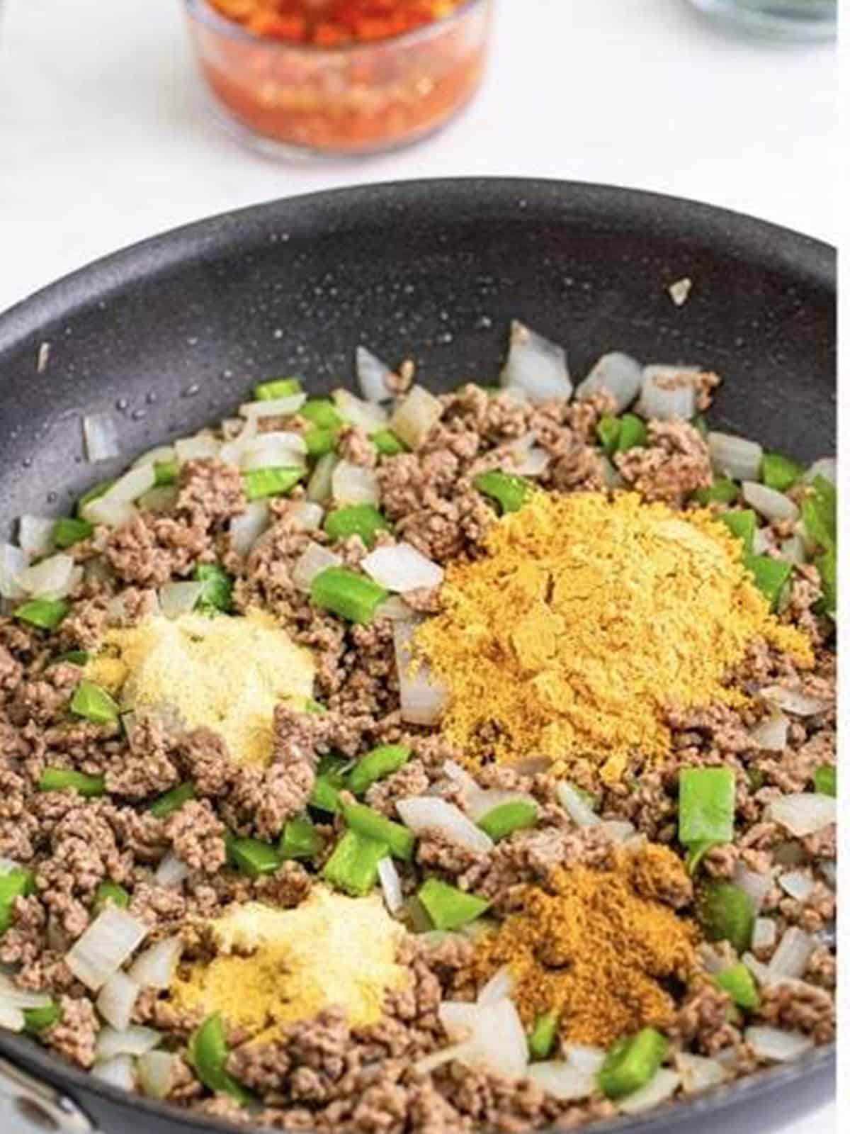 Stirring taco seasoning, garlic powder, onion powder, and cumin into the cooked beef for Taco Joes.