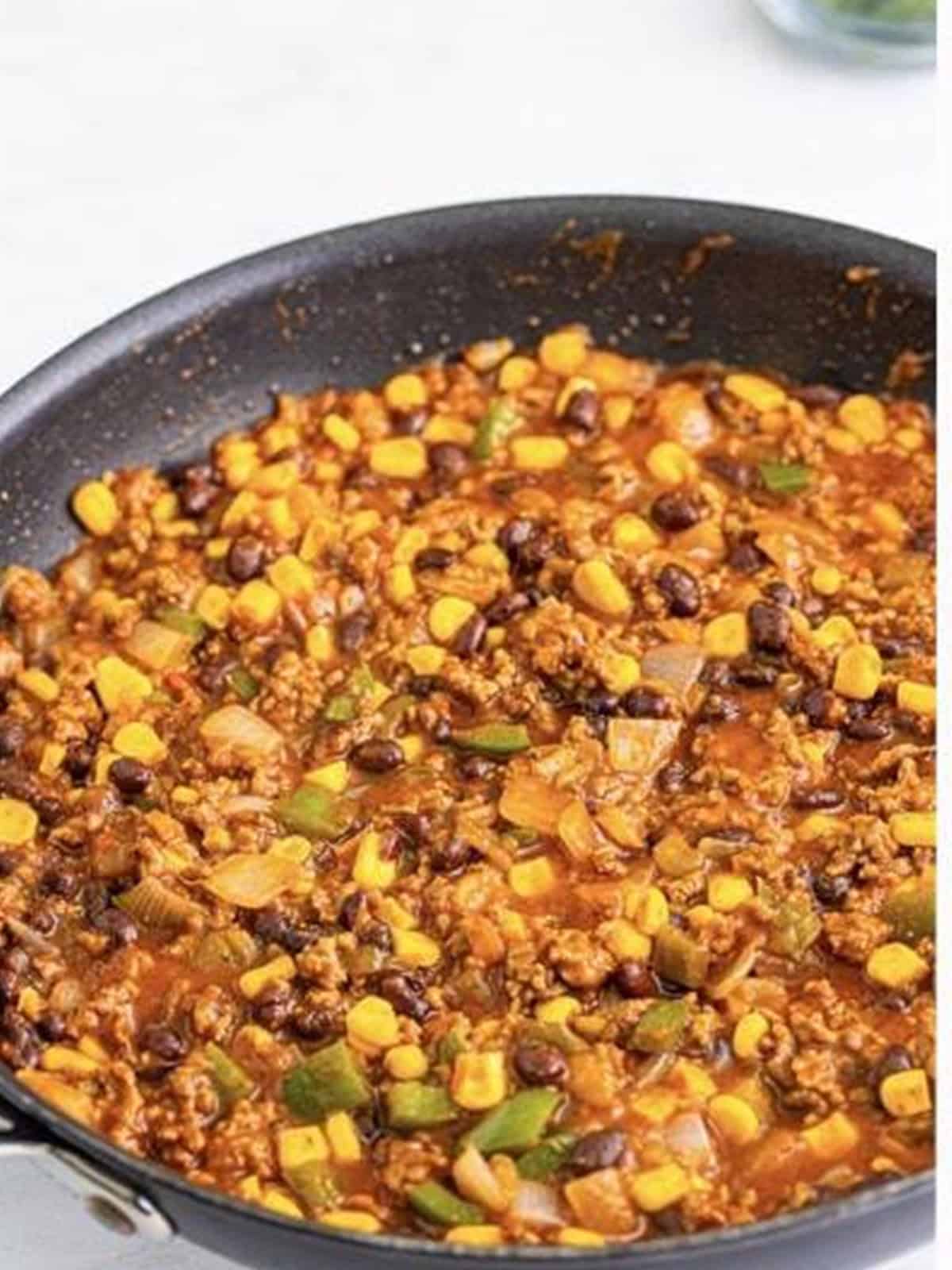 Simmering the saucy Taco Joes meat mixture in the skillet until slightly thickened.