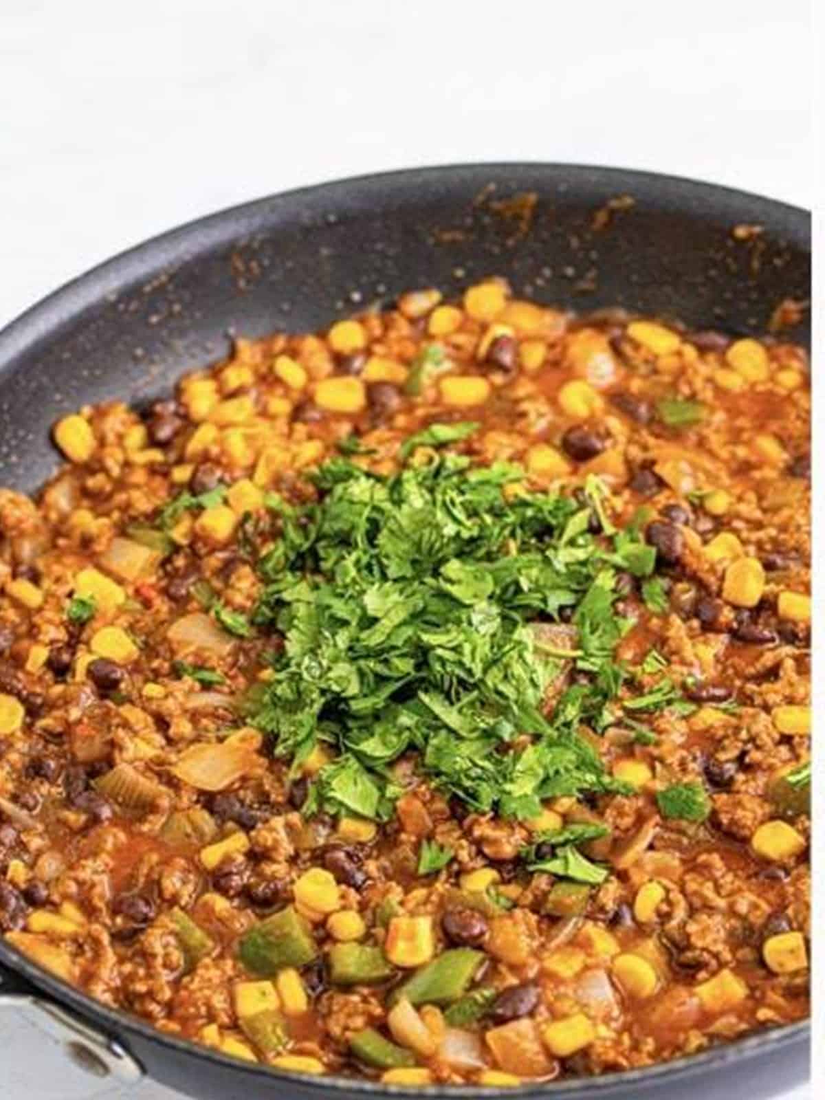 Stirring fresh chopped cilantro into the finished Taco Joes filling.