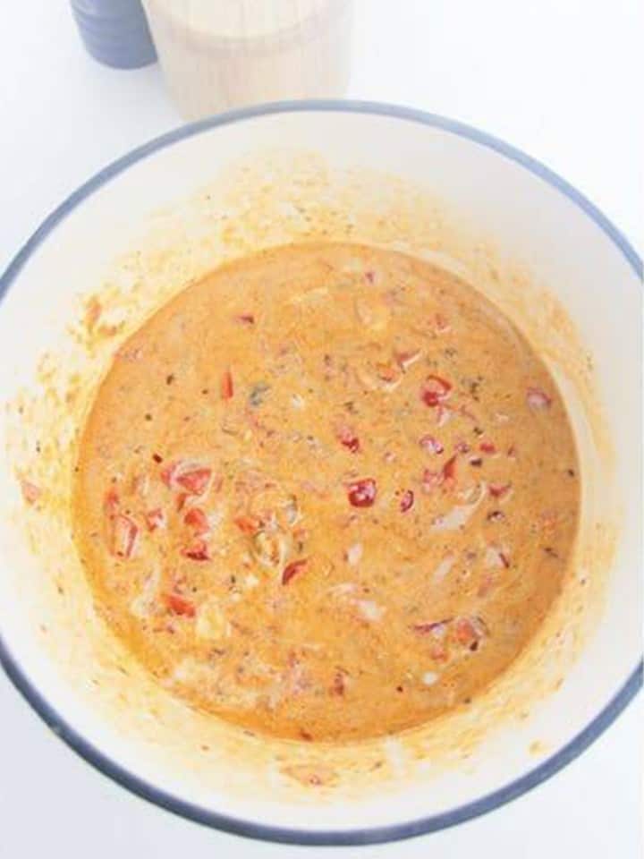 Coconut milk stirred into the curry base making a creamy orange broth.