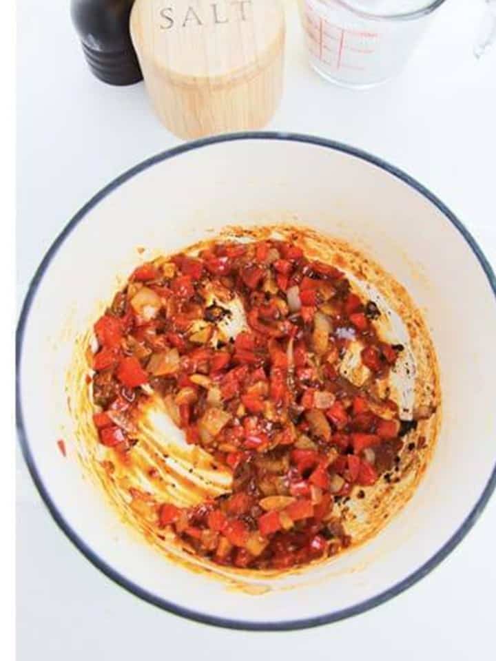 Red curry paste stirred into the aromatics and cooked until fragrant.