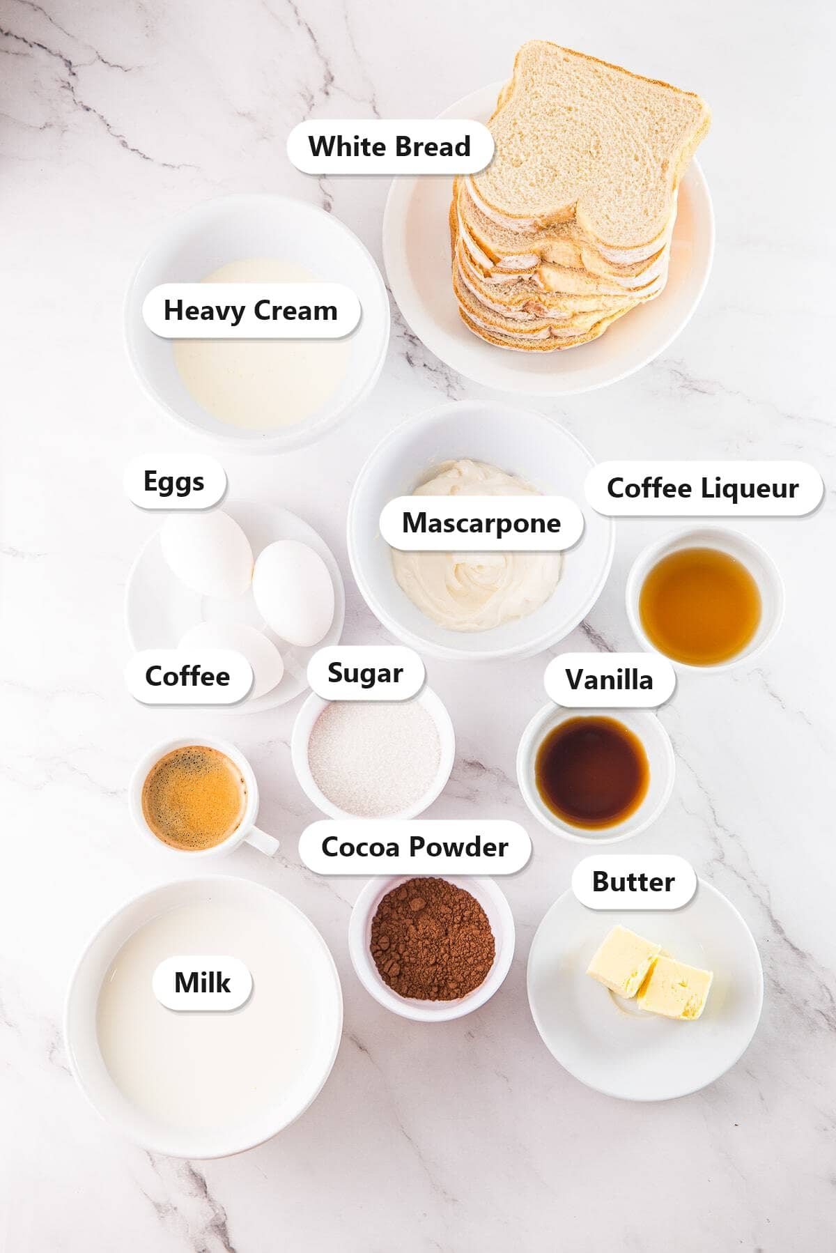 Labeled ingredients for Tiramisu French Toast including mascarpone, heavy cream, coffee liqueur, eggs, milk, and cocoa powder.