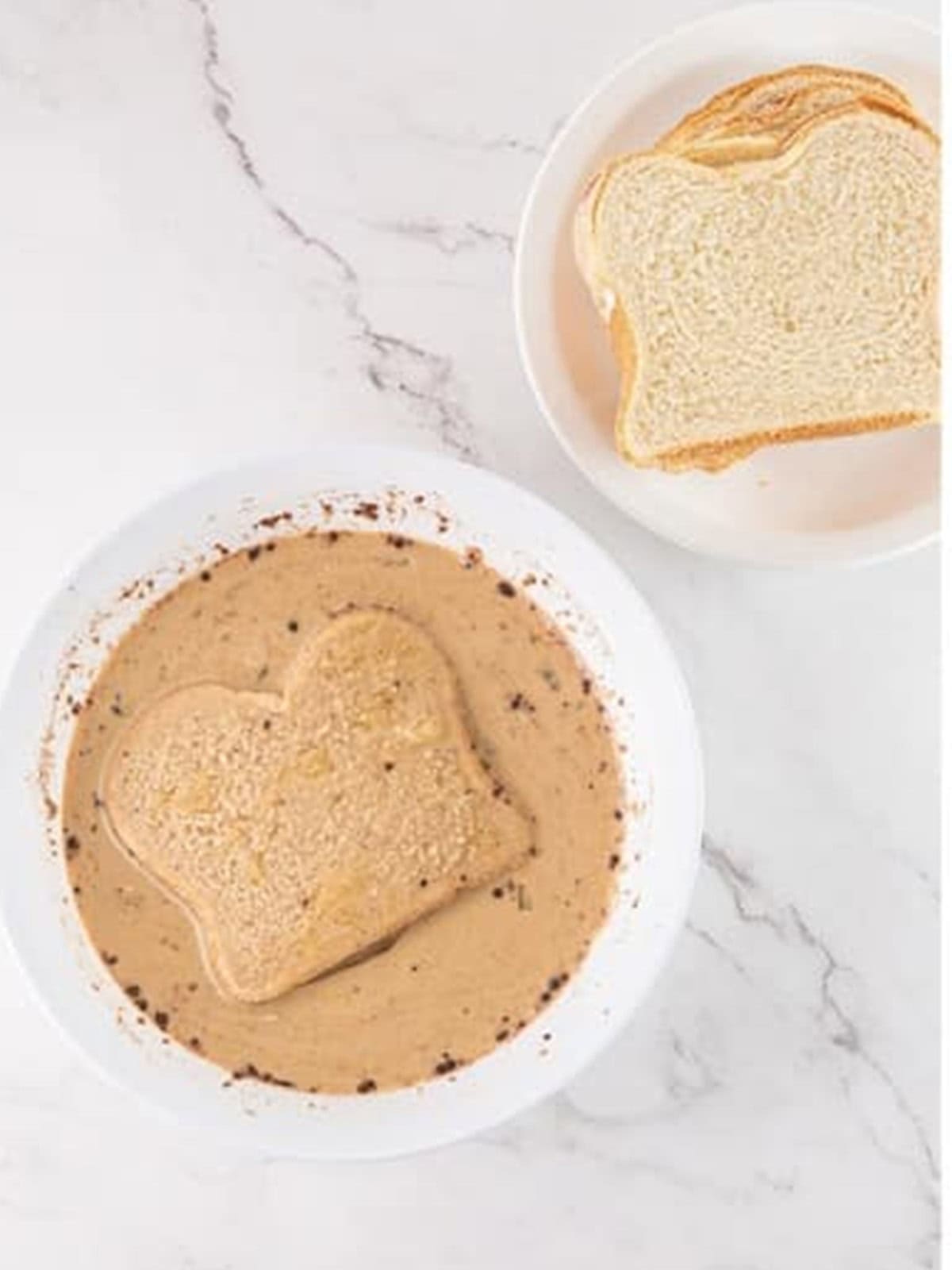 Dipping a slice of white bread into the coffee custard for Tiramisu French Toast.