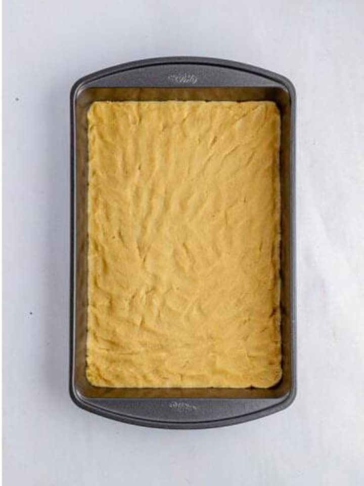 Toffee bar shortbread dough pressed evenly into a baking pan.