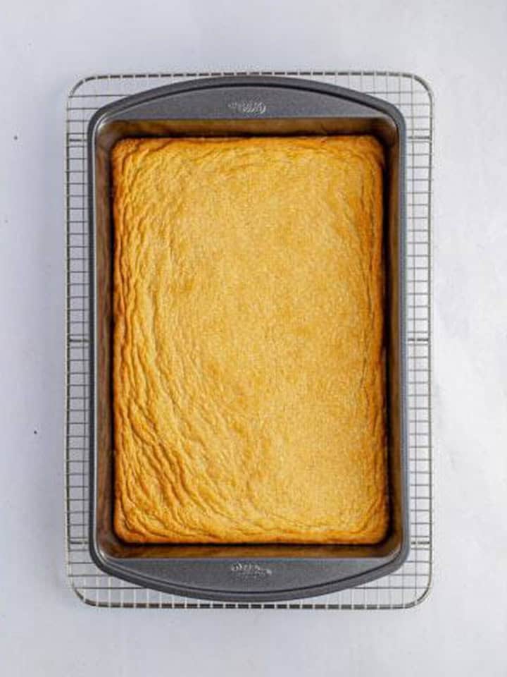 Golden brown baked shortbread base for toffee bars cooling on a wire rack.