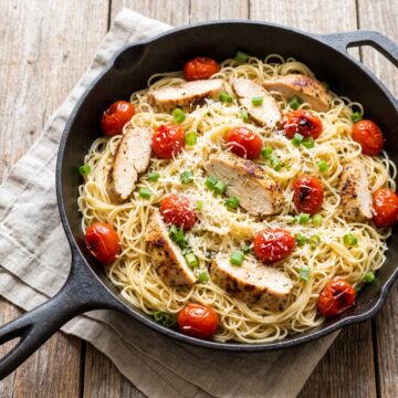 A skillet of Tomato Chicken Pasta with blistered cherry tomatoes and parmesan.
