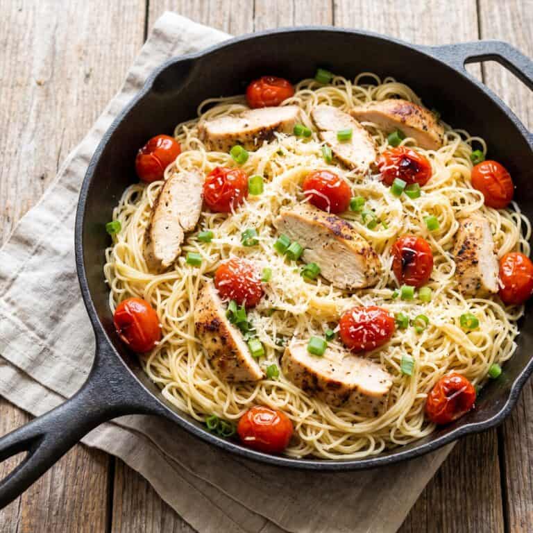 A skillet of Tomato Chicken Pasta with blistered cherry tomatoes and parmesan.