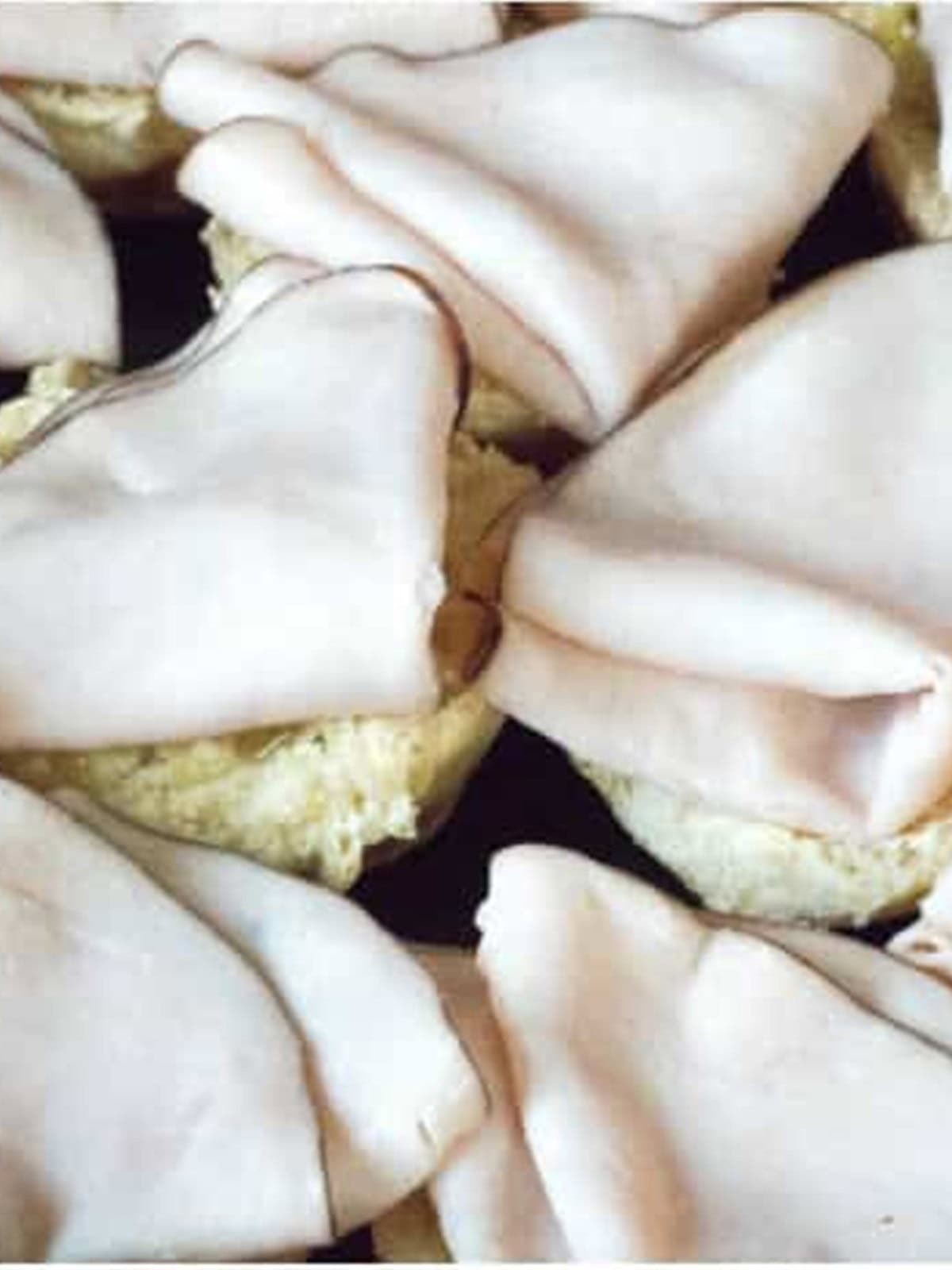 Folded deli turkey slices layered over the slider roll bottoms.