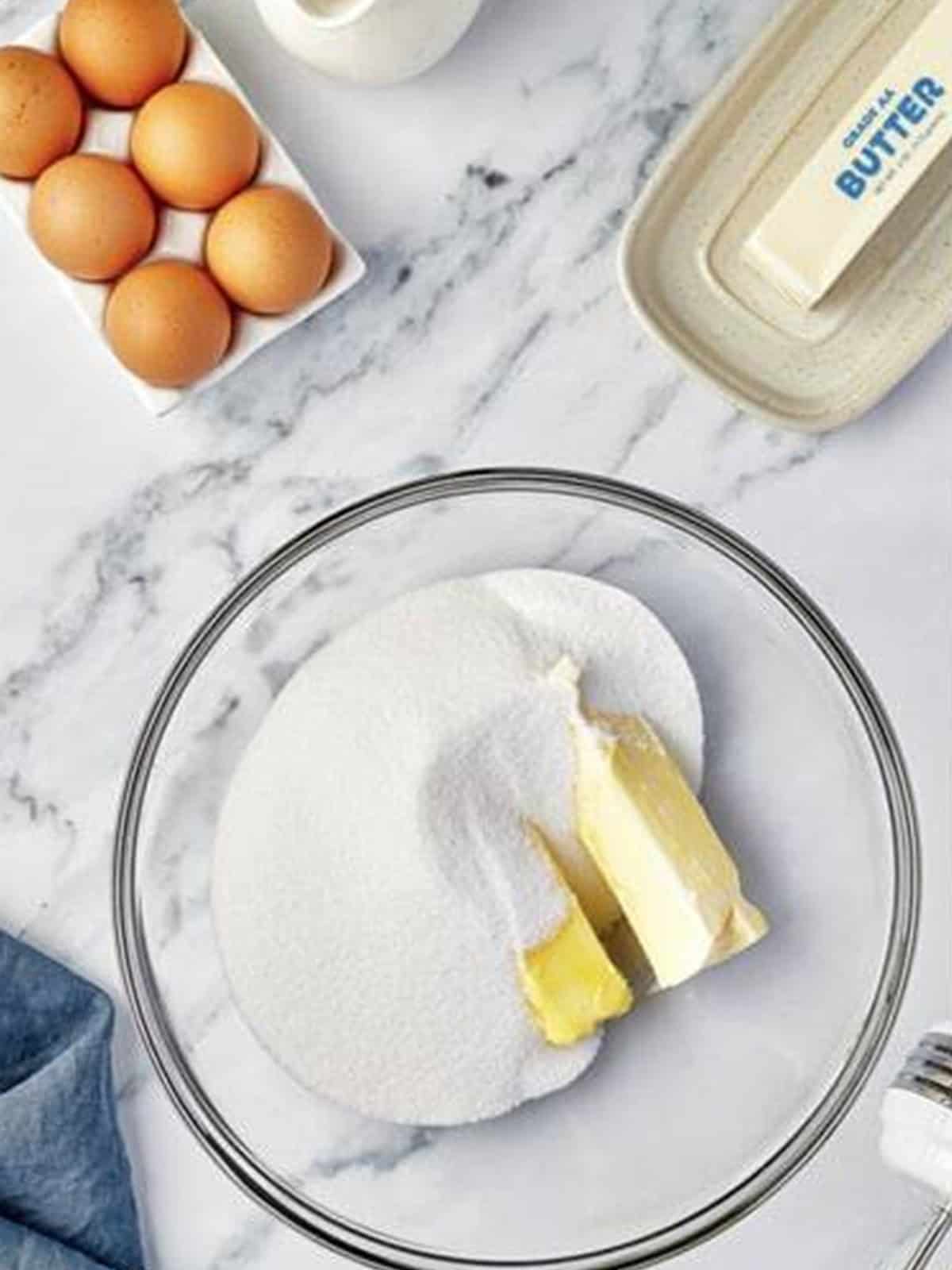 Butter and granulated sugar in a glass mixing bowl ready to cream for Valentines Day Cupcakes.