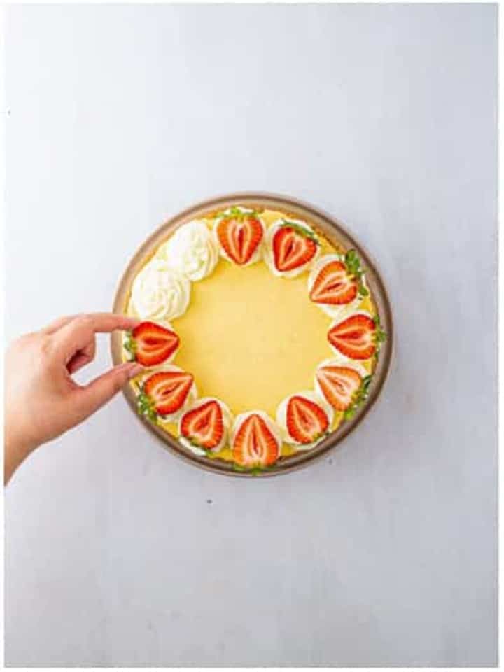 Fresh strawberry slices arranged over whipped cream swirls on the chilled vanilla bean cheesecake.