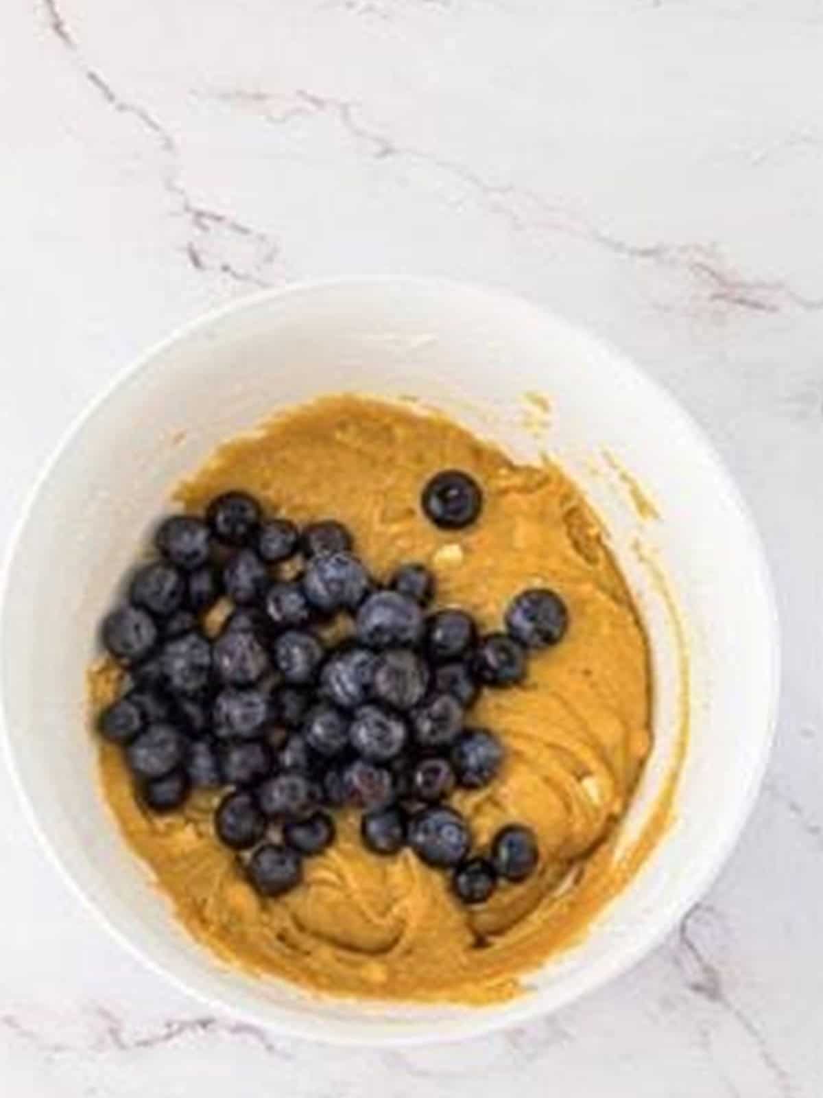 Fresh blueberries added on top of the blondie batter ready to be gently folded in.