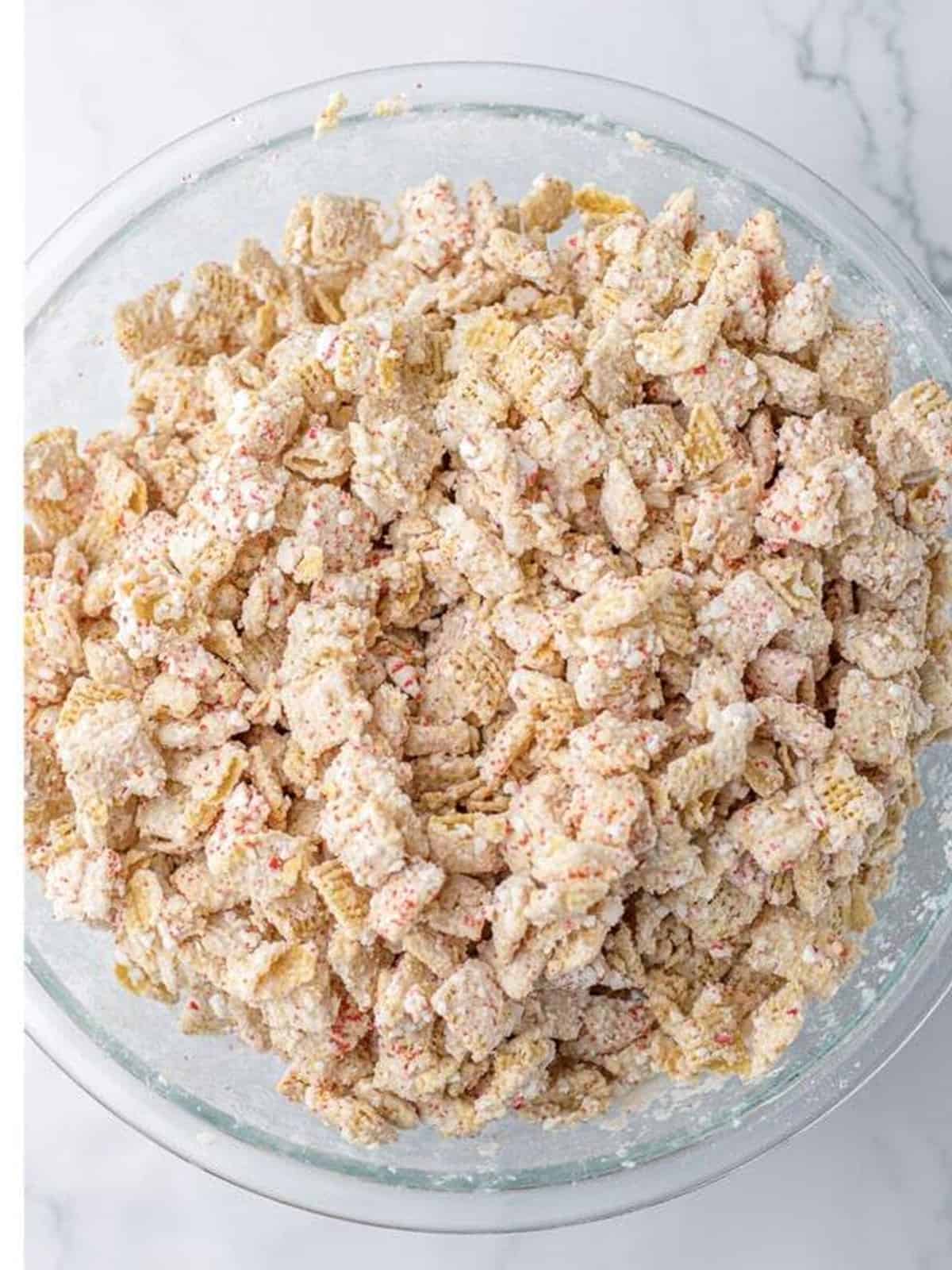 White chocolate chex mix stirred so the crushed peppermint pieces are evenly distributed.