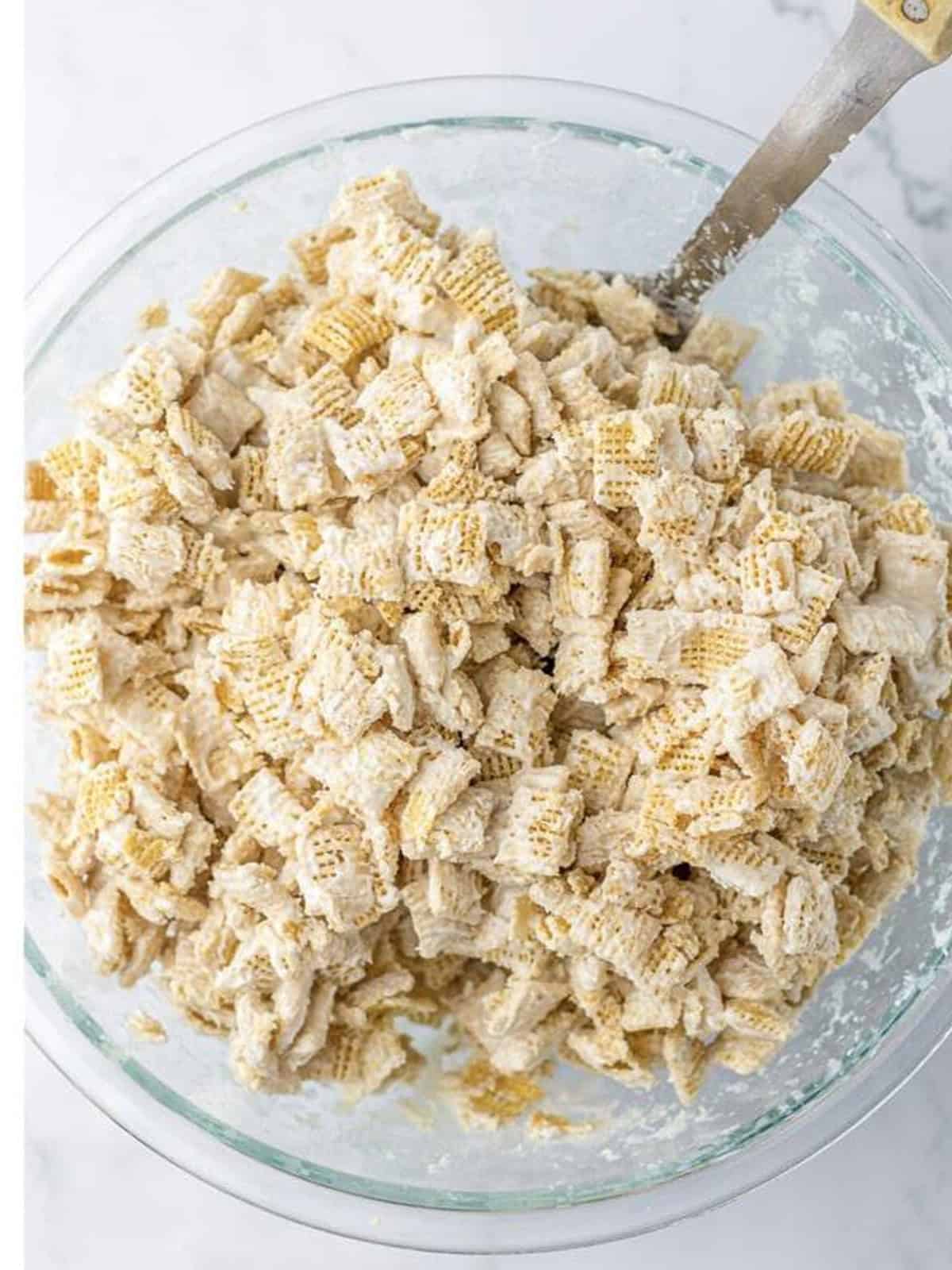 Rice chex cereal stirred until fully coated in melted white chocolate for white chocolate chex mix.