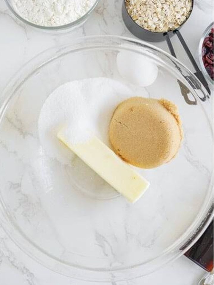 Butter, granulated sugar, and brown sugar in a glass mixing bowl for White Chocolate Cranberry Cookies.