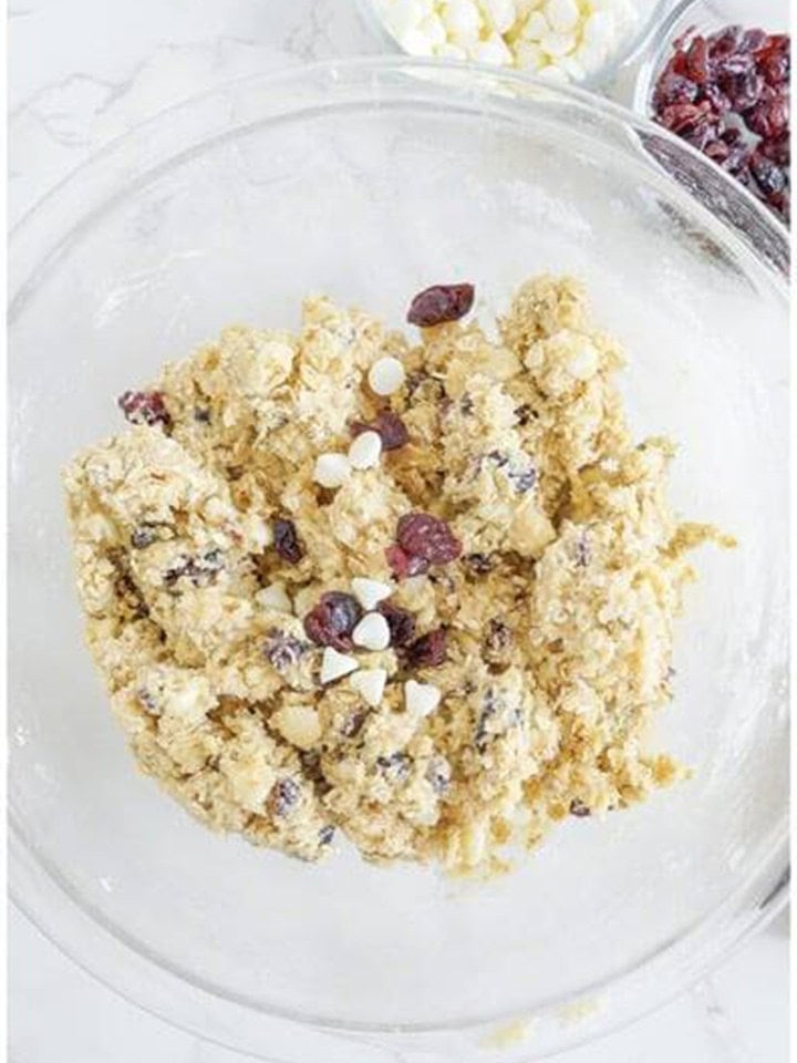 Folding quick oats, dried cranberries, and white chocolate chips into the cookie dough.