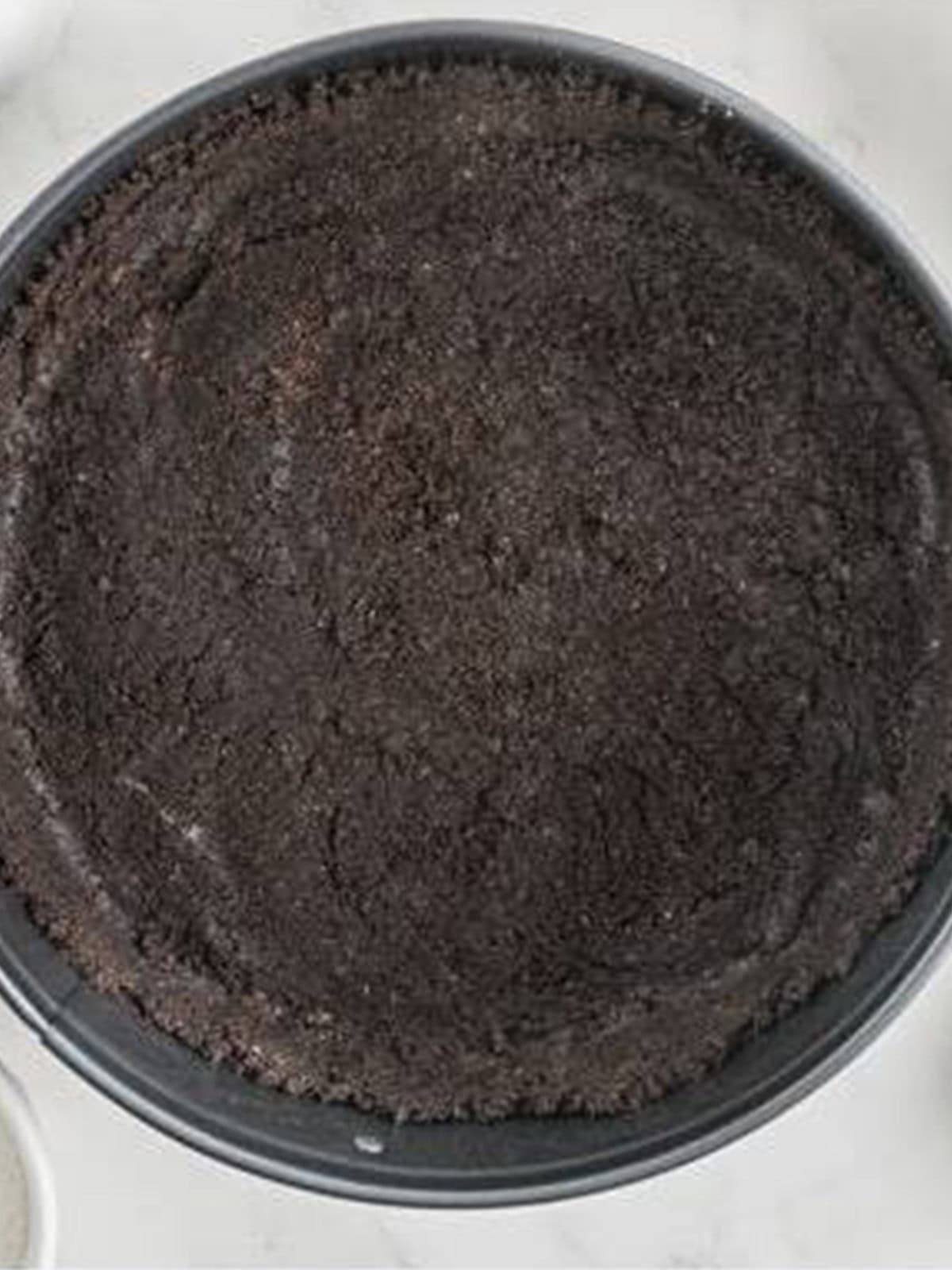 Oreo crumb crust pressed into a springform pan for White Chocolate Raspberry Cheesecake.