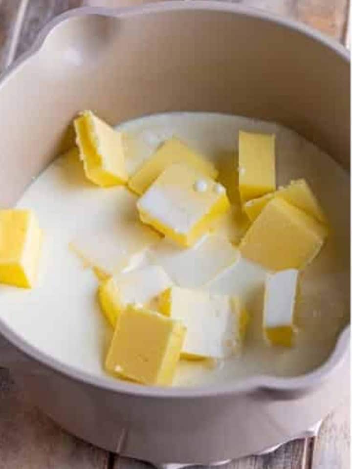 Heavy cream and cubed butter in a saucepan for White Chocolate Sauce.