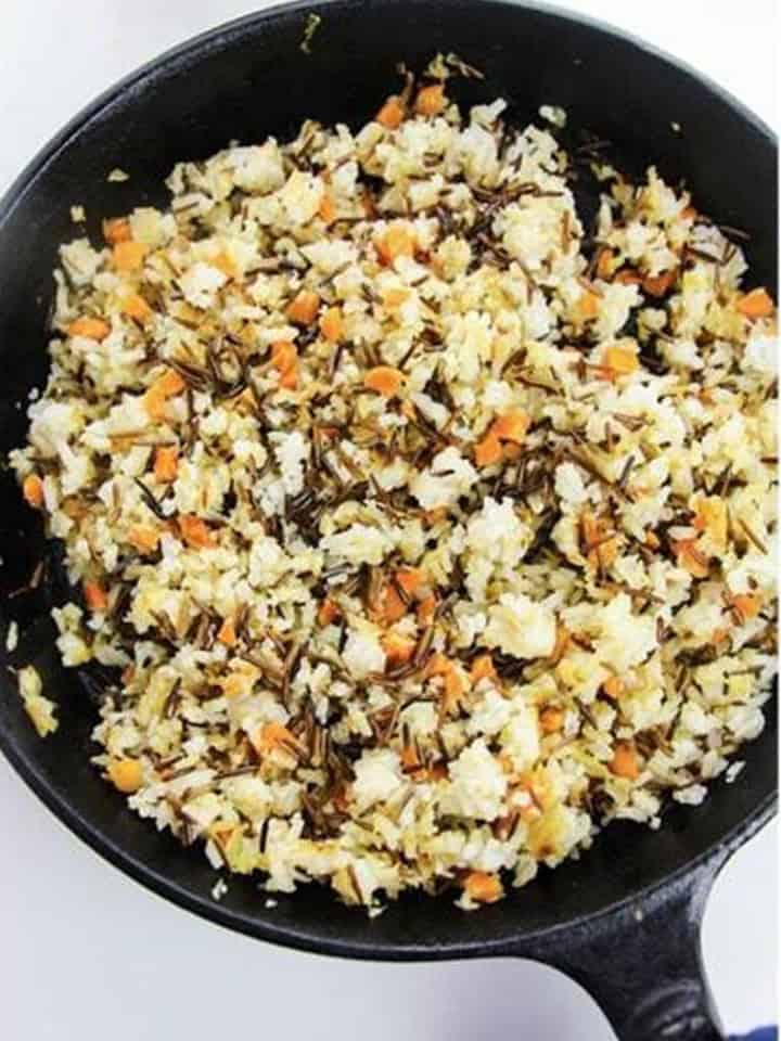 Stirring and seasoning the Wild Rice Pilaf with salt and pepper.