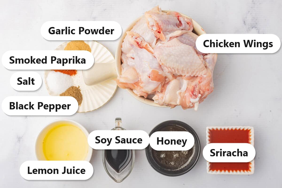Labeled ingredients for air fryer chicken wings including chicken wings, garlic powder, smoked paprika, salt, black pepper, honey, soy sauce, sriracha, and lemon juice.