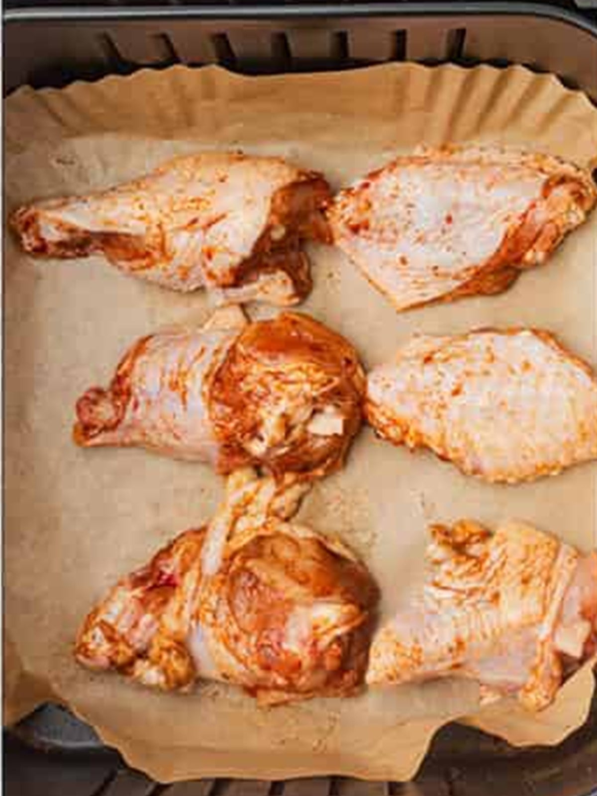 Seasoned chicken wings arranged in a single layer in the air fryer basket.