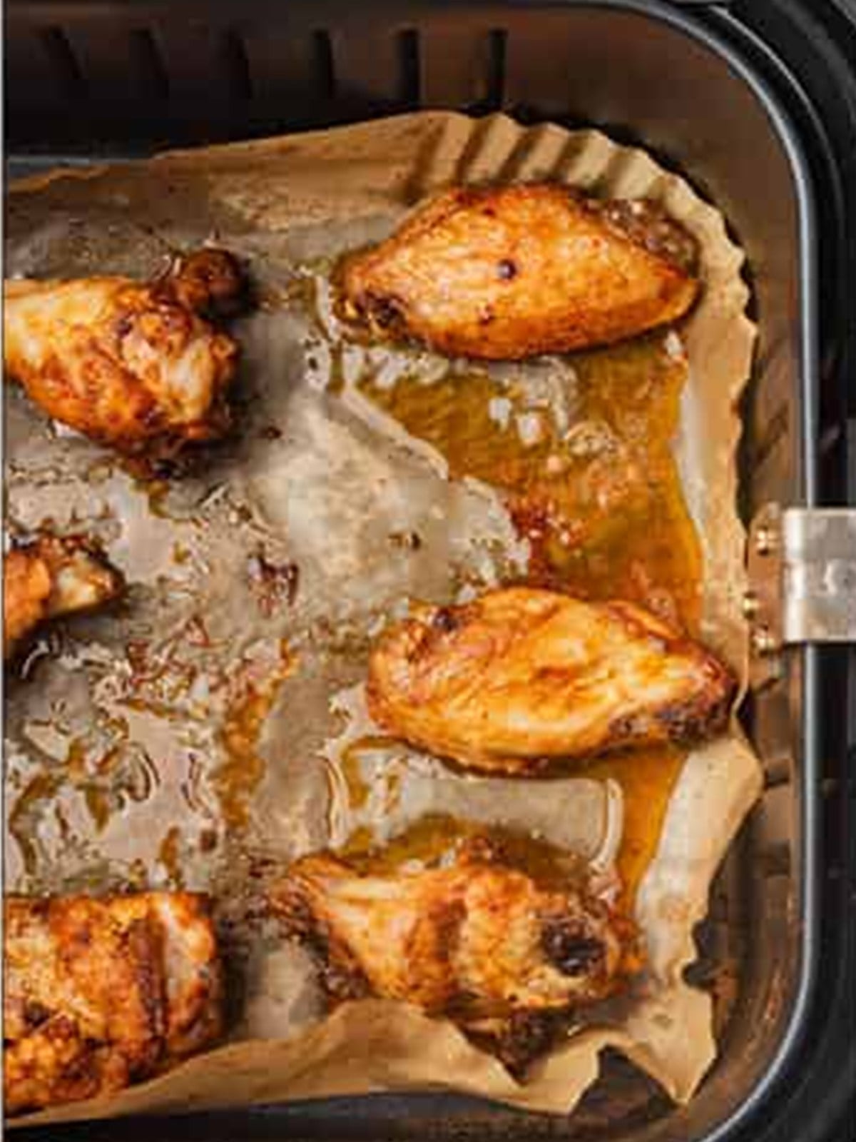 Golden brown crispy chicken wings in the air fryer basket after cooking.