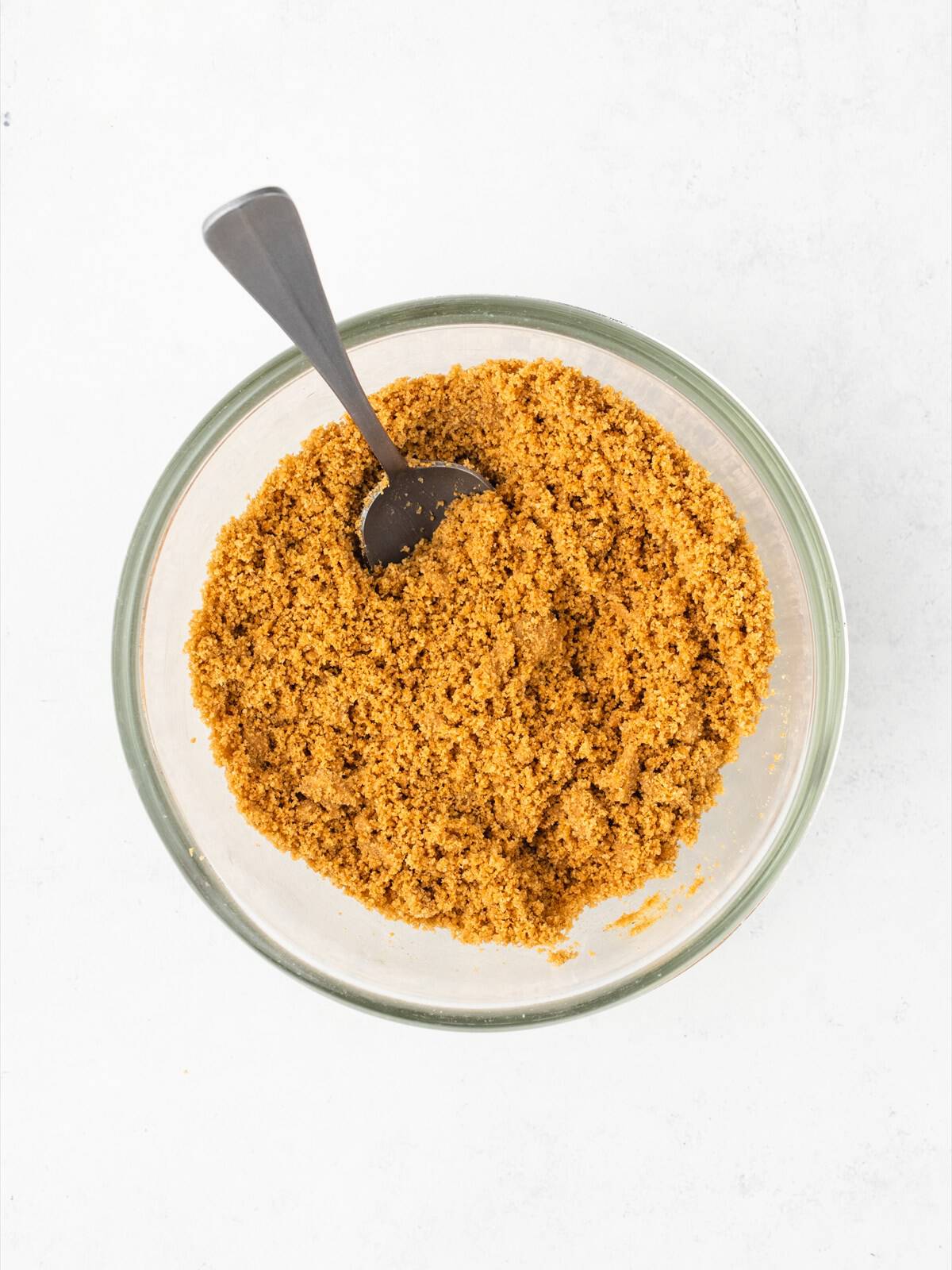 Graham cracker crumbs and melted butter stirred together in a bowl until the mixture looks like wet sand.